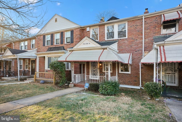 multi unit property featuring covered porch and a front lawn