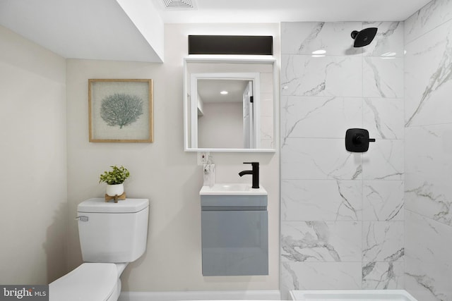 bathroom featuring tiled shower, vanity, and toilet