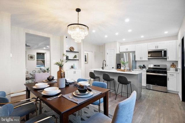 dining space featuring sink, an inviting chandelier, and light wood-type flooring