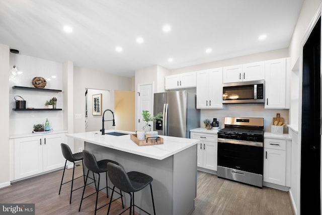 kitchen with stainless steel appliances, sink, a kitchen island with sink, and white cabinets