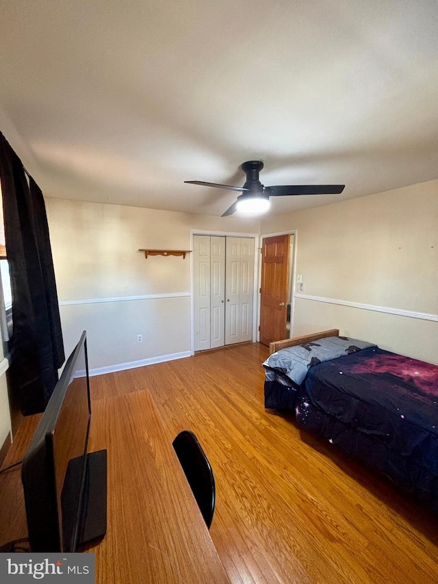 bedroom with ceiling fan, wood-type flooring, and a closet