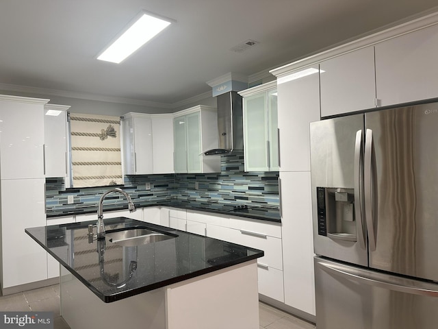 kitchen featuring sink, stainless steel fridge, an island with sink, and wall chimney exhaust hood