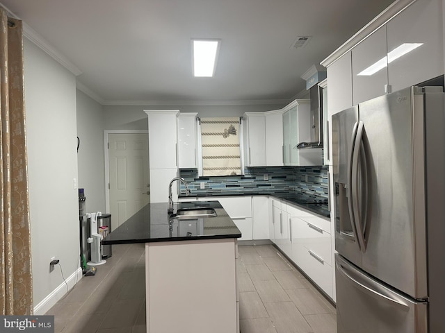 kitchen with sink, a kitchen island with sink, backsplash, stainless steel refrigerator with ice dispenser, and white cabinets