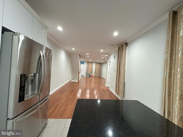 kitchen with stainless steel refrigerator with ice dispenser, ornamental molding, white cabinets, and light wood-type flooring