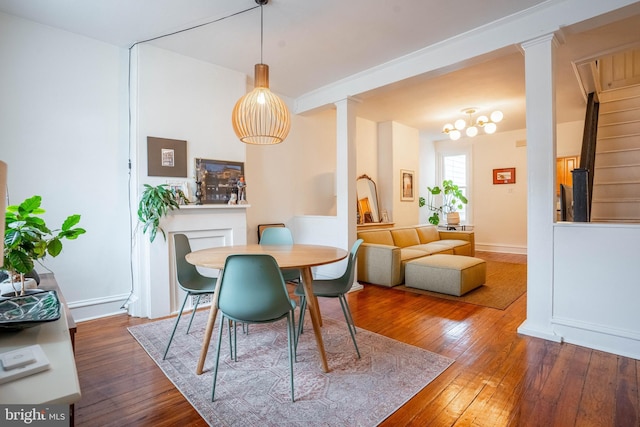 dining space featuring wood-type flooring and decorative columns