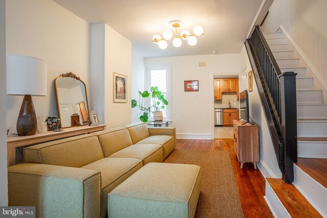 living room with dark hardwood / wood-style flooring, a notable chandelier, and sink