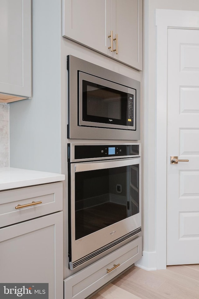 interior details with tasteful backsplash, light hardwood / wood-style floors, and appliances with stainless steel finishes