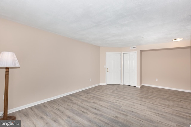 spare room with a textured ceiling and light wood-type flooring