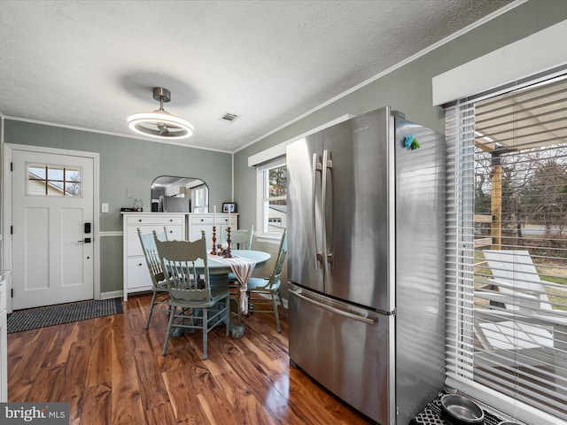 dining area featuring crown molding, dark wood-type flooring, and a textured ceiling