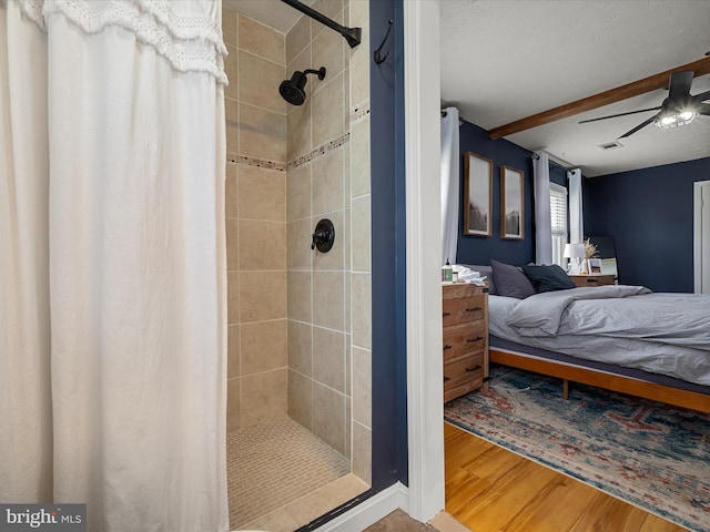 bathroom with ceiling fan, curtained shower, wood-type flooring, and beamed ceiling