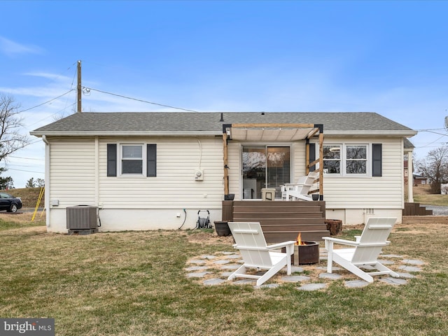 rear view of property featuring a yard, central AC, and an outdoor fire pit