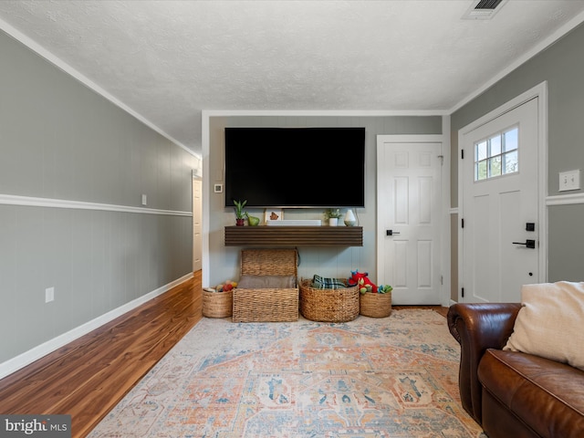 living room featuring crown molding, hardwood / wood-style flooring, and a textured ceiling