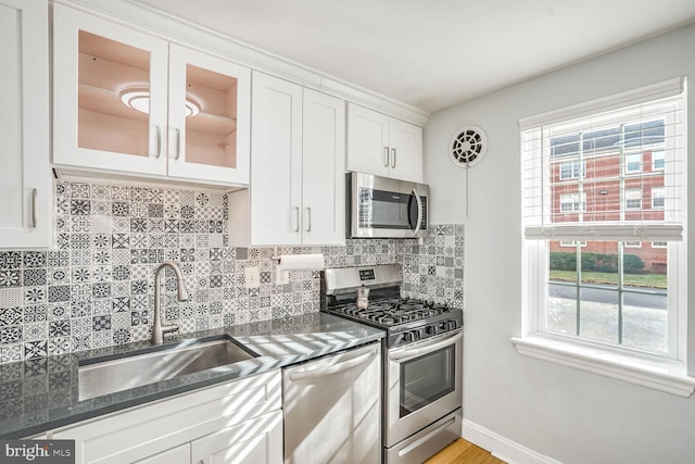 kitchen featuring appliances with stainless steel finishes, tasteful backsplash, sink, dark stone countertops, and white cabinets