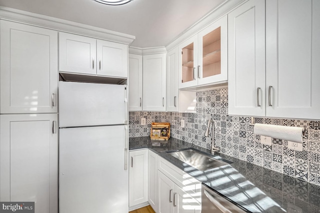 kitchen featuring sink, white refrigerator, dark stone counters, decorative backsplash, and white cabinets