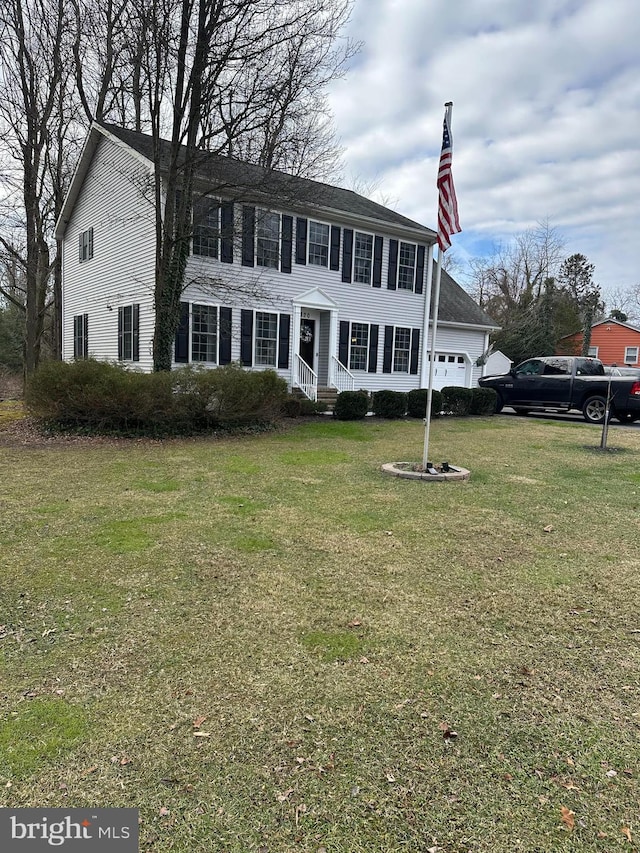 colonial home featuring a garage and a front lawn