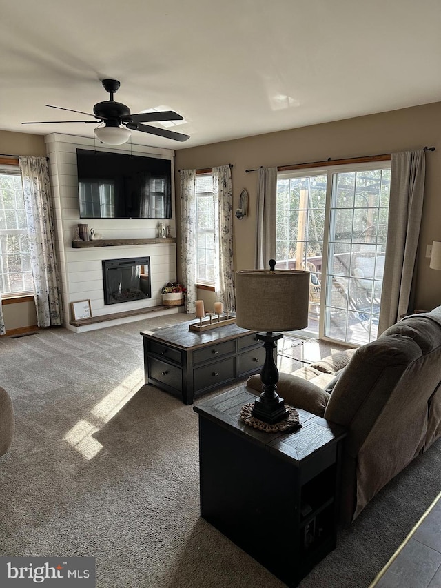 carpeted living room with a large fireplace and ceiling fan