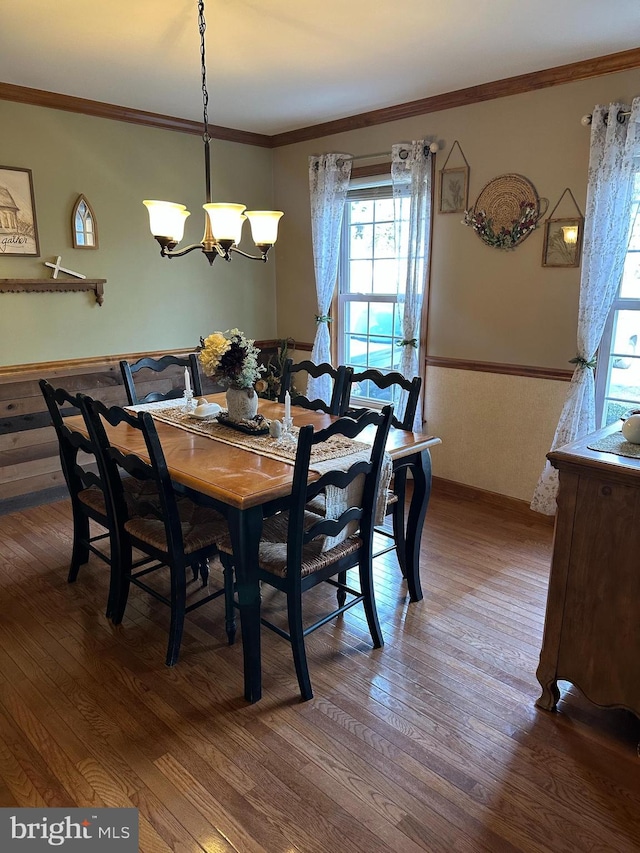 dining area with an inviting chandelier, hardwood / wood-style flooring, and ornamental molding