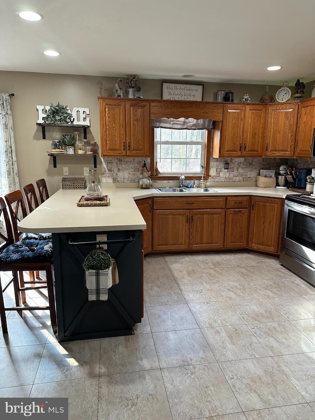 kitchen with sink, stainless steel range with electric stovetop, tasteful backsplash, a kitchen bar, and kitchen peninsula