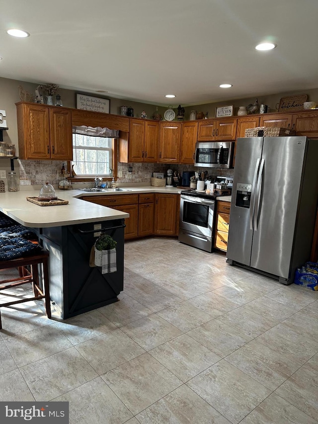 kitchen featuring sink, appliances with stainless steel finishes, backsplash, a kitchen breakfast bar, and kitchen peninsula