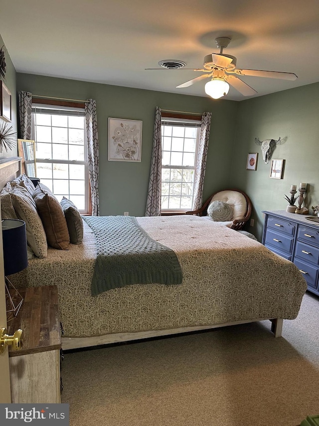 bedroom with ceiling fan, carpet floors, and multiple windows