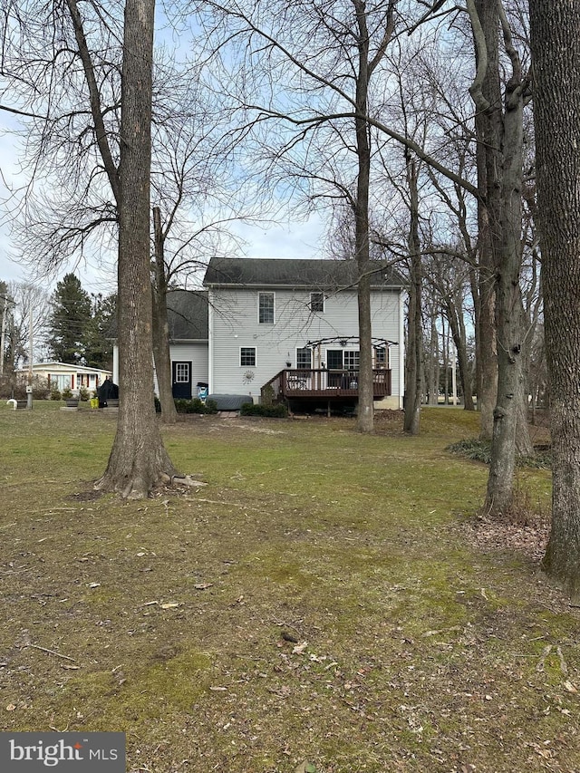 back of property featuring a wooden deck and a lawn