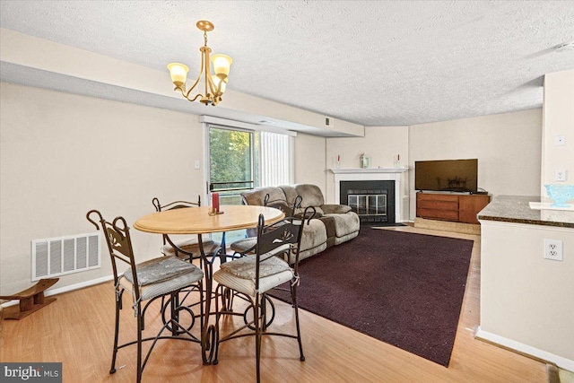 dining area featuring a chandelier, a textured ceiling, and light hardwood / wood-style floors