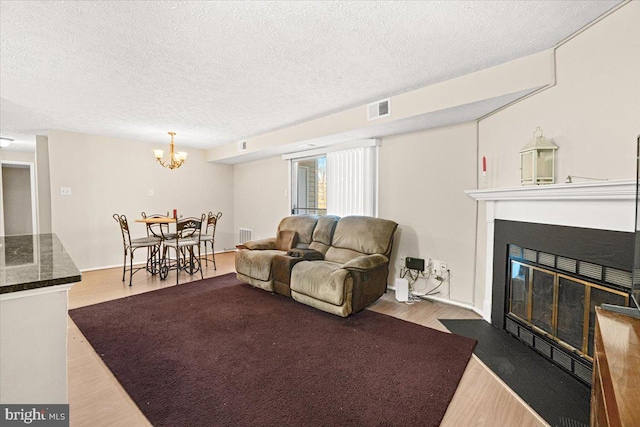 living room featuring an inviting chandelier, a textured ceiling, and light hardwood / wood-style floors