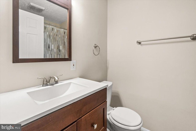 bathroom with vanity, a textured ceiling, and toilet