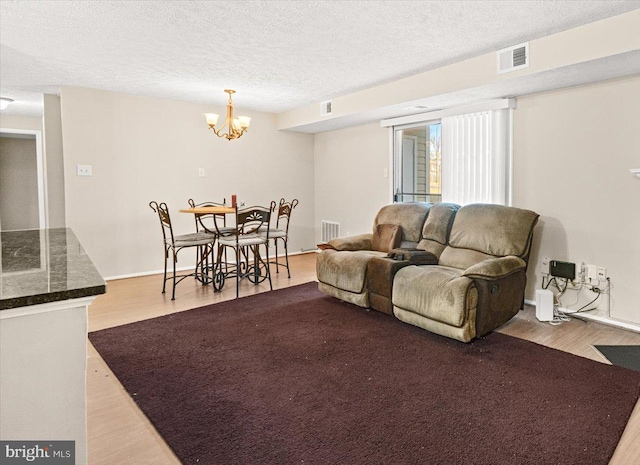 living room featuring a chandelier, a textured ceiling, and light wood-type flooring