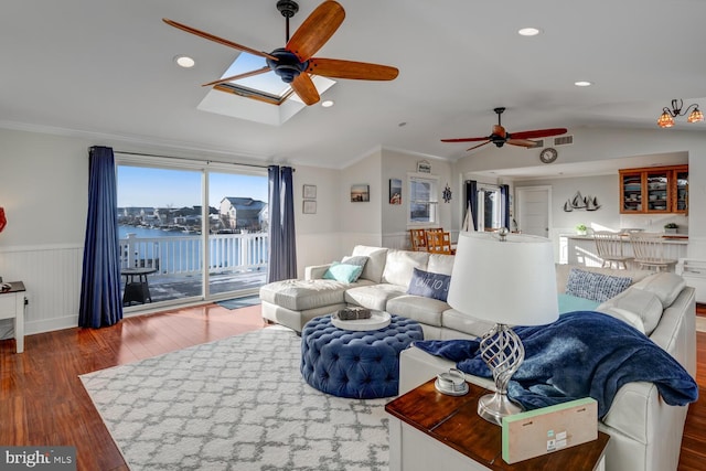 living room with wood-type flooring, a water view, ornamental molding, and lofted ceiling with skylight