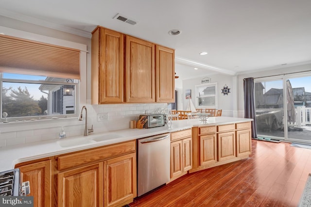 kitchen featuring sink, dishwasher, tasteful backsplash, ornamental molding, and light hardwood / wood-style floors