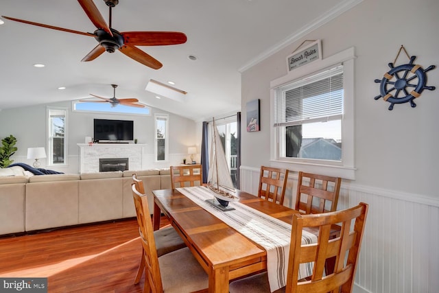 dining area featuring crown molding, vaulted ceiling, ceiling fan, and light wood-type flooring