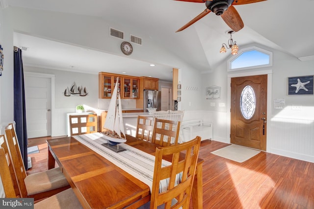 dining room with vaulted ceiling, crown molding, an inviting chandelier, and light wood-type flooring