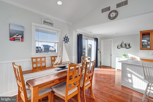 dining area featuring ornamental molding, vaulted ceiling, and light hardwood / wood-style flooring