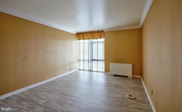 unfurnished room featuring ornamental molding, radiator heating unit, and light wood-type flooring