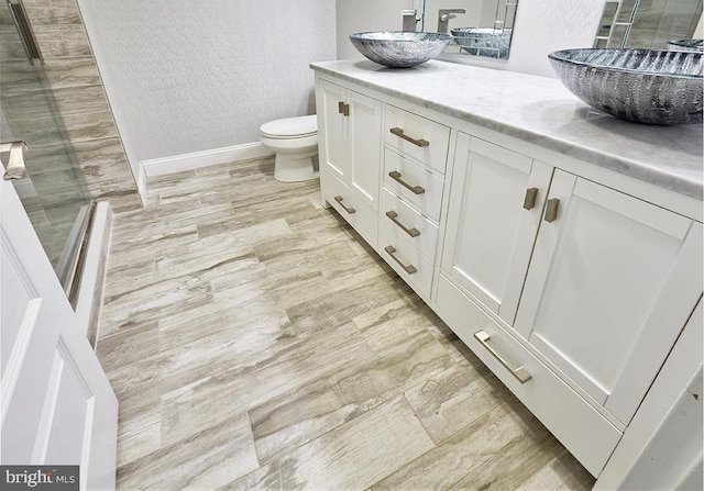 bathroom with hardwood / wood-style floors, vanity, toilet, and a shower with shower door