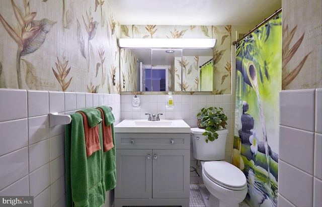 bathroom with vanity, toilet, and tile walls