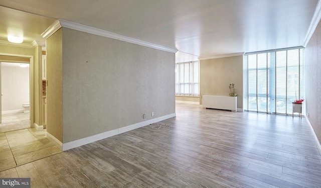 empty room featuring crown molding, wood-type flooring, and floor to ceiling windows