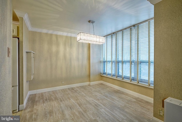 unfurnished dining area with hardwood / wood-style flooring, crown molding, and a chandelier