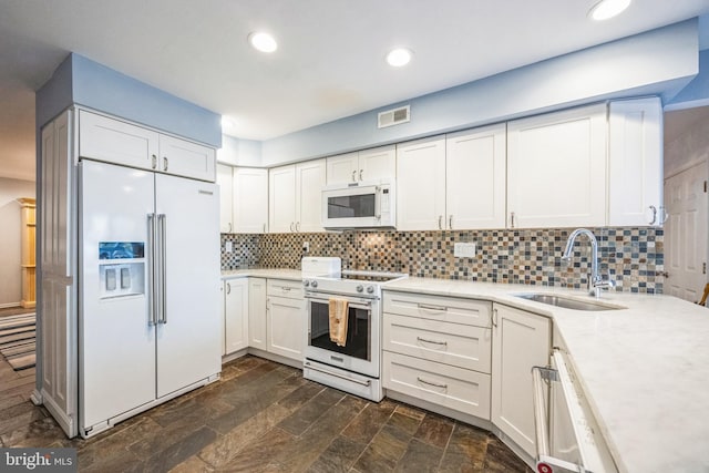 kitchen featuring backsplash, white appliances, sink, and white cabinets