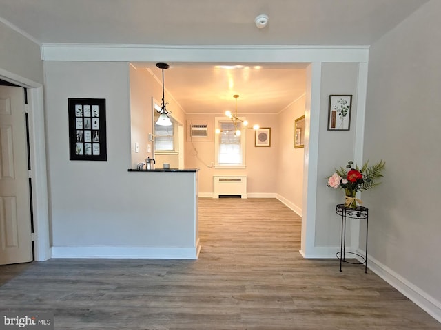 kitchen featuring hardwood / wood-style flooring, an inviting chandelier, hanging light fixtures, radiator heating unit, and ornamental molding