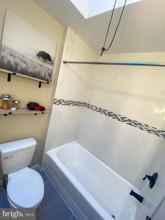 bathroom featuring tiled shower / bath, toilet, and tile patterned flooring