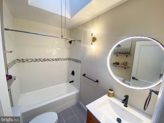 full bathroom with vanity, tiled shower / bath combo, a skylight, and toilet