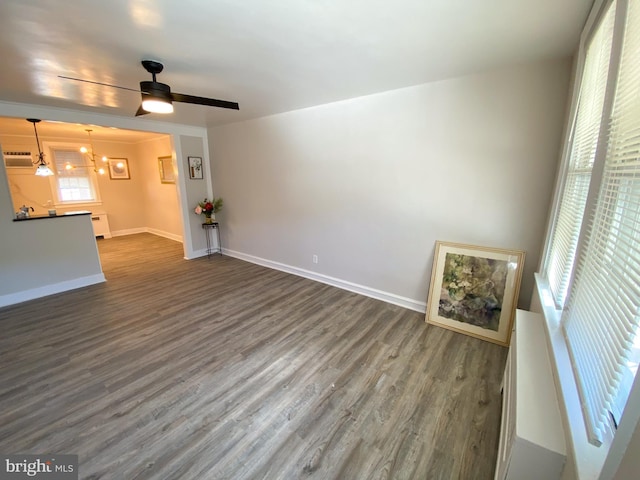 unfurnished living room featuring dark wood-type flooring and ceiling fan