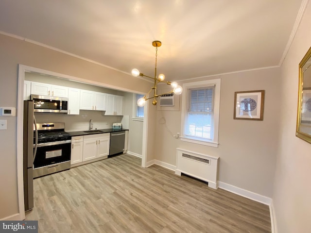 kitchen with sink, white cabinetry, radiator heating unit, stainless steel appliances, and decorative light fixtures