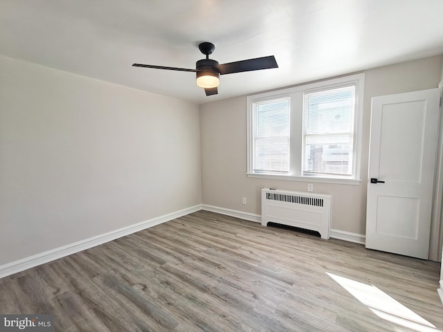 empty room featuring radiator heating unit, ceiling fan, and light wood-type flooring