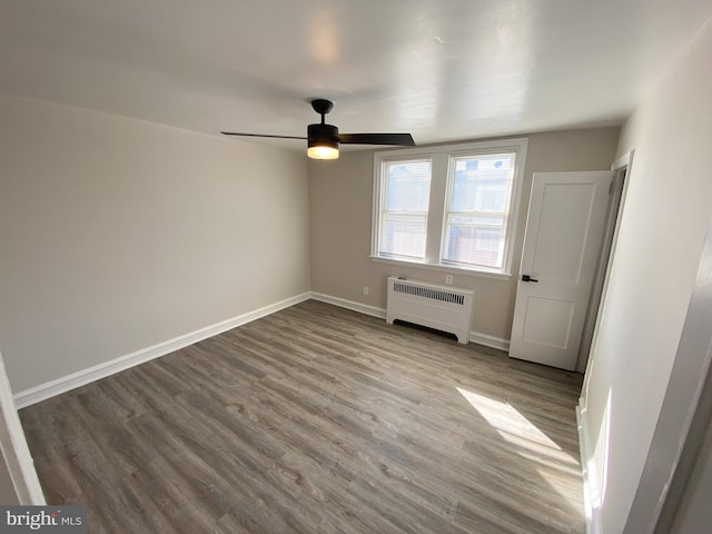 unfurnished bedroom with ceiling fan, radiator heating unit, and wood-type flooring