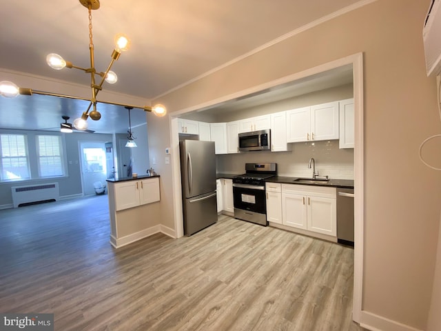 kitchen with sink, white cabinetry, decorative light fixtures, radiator, and stainless steel appliances