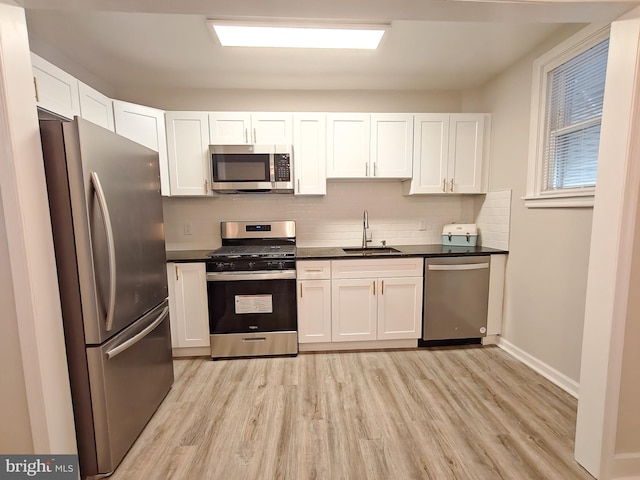 kitchen with sink, white cabinetry, tasteful backsplash, light hardwood / wood-style flooring, and stainless steel appliances