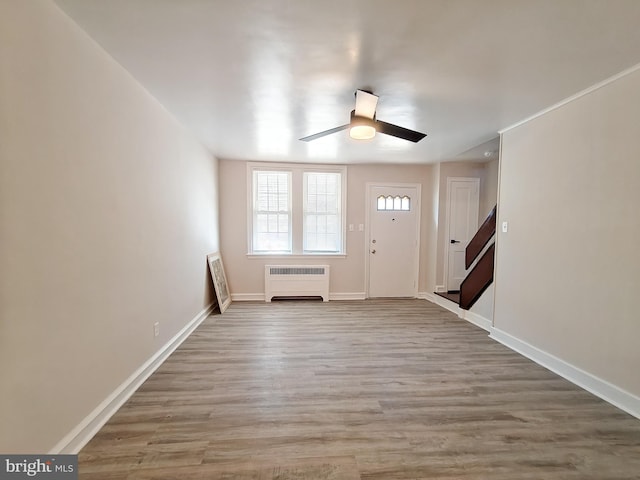 foyer entrance featuring hardwood / wood-style flooring, ceiling fan, and radiator heating unit